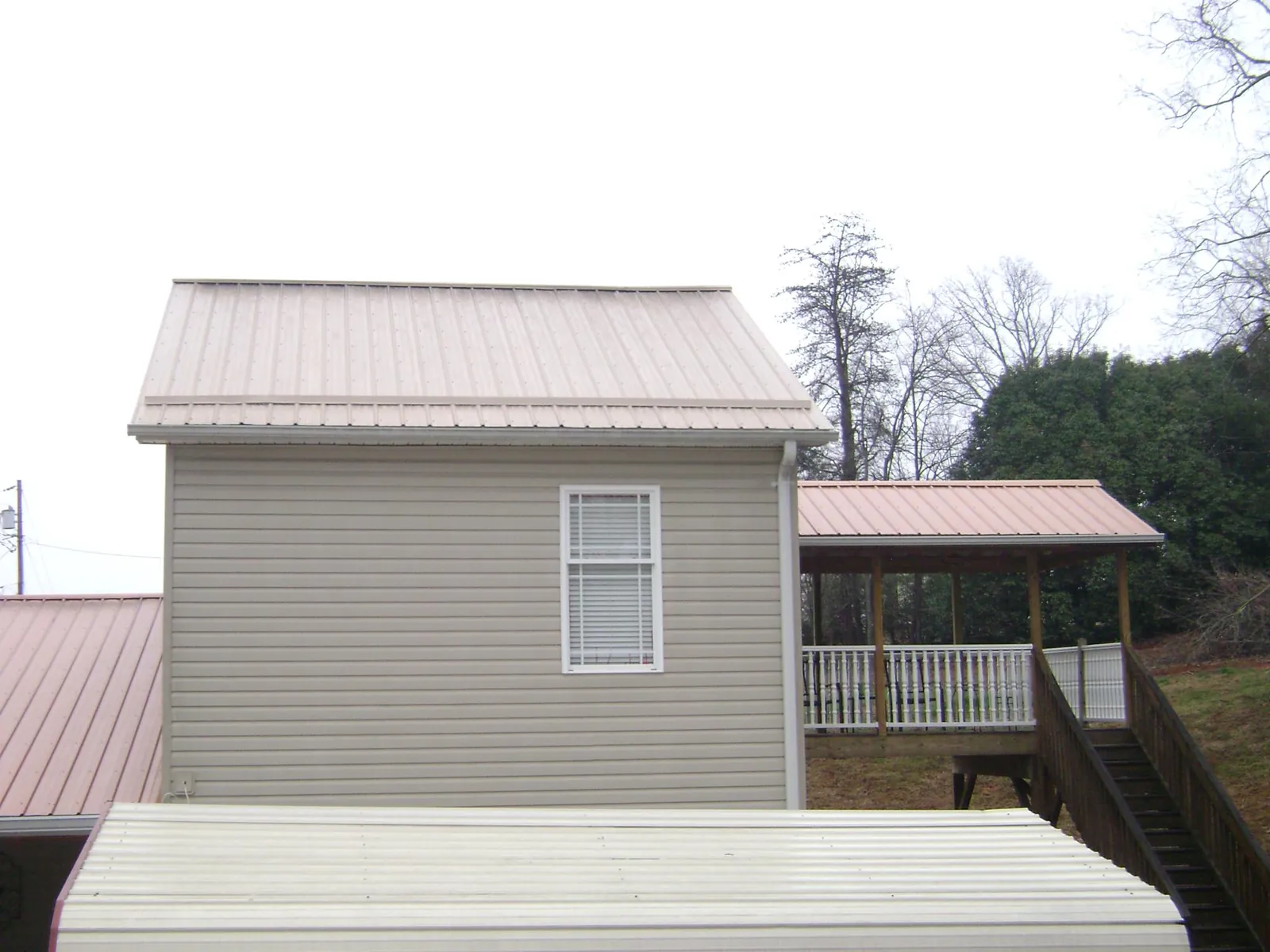 Tan metal roofs on a two story addition and attached porch, from a Roof Replacement job in Englewood