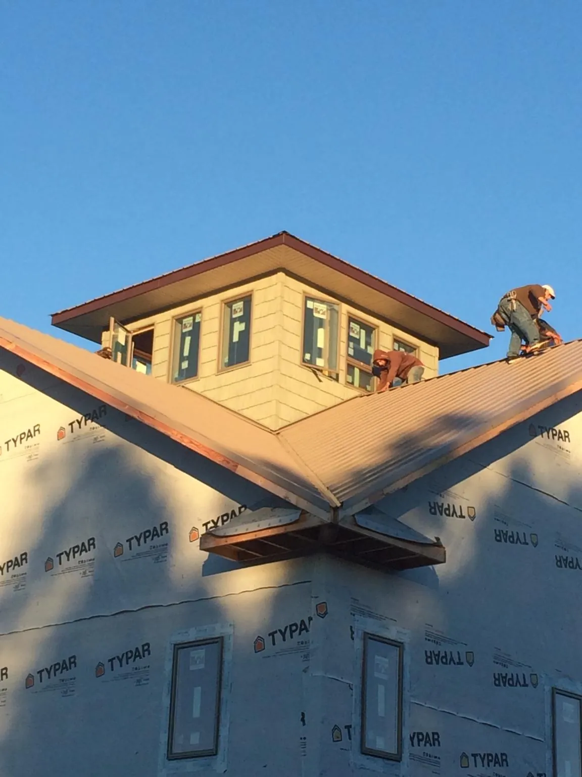 Roofers working around a rooftop cupola on a new metal roof at sunset — Roof Waterproofing in Englewood by Roofing Brothers